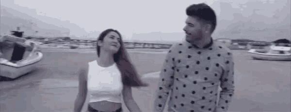a man and a woman are holding hands on a beach .