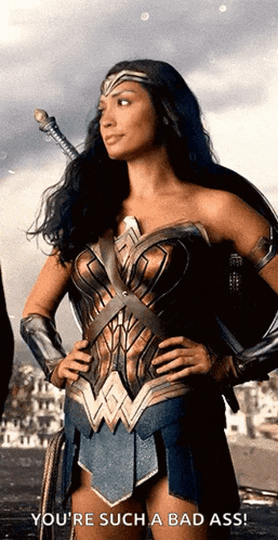 a woman in a wonder woman costume has her hands on her hips and says you 're such a bad ass