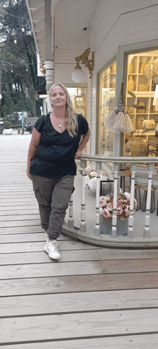 a woman standing on a porch with flowers in front of her