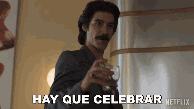 a man holding a glass with hay que celebrar written on it