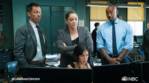 a group of people looking at a computer screen with the hashtag lawandorder