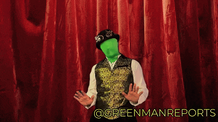 a man with a green face stands in front of a red curtain