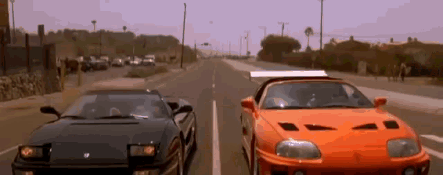 a black car and an orange car are driving down a highway