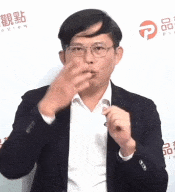 a man in a suit and glasses is making a gesture with his hand