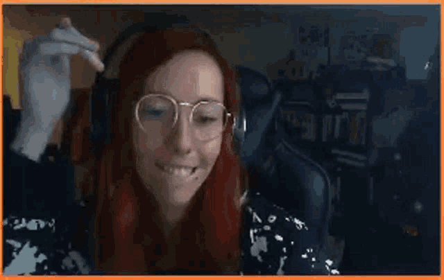 a woman with red hair and glasses is wearing headphones while smoking a cigarette .