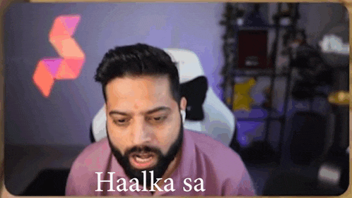 a man with a beard is sitting in a chair with the words haalka sa on the screen .