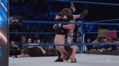 a wrestling match is going on in a ring with a crowd watching