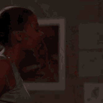 a woman with her hair in a ponytail is standing in a dark room .