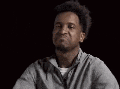 a man in a gray shirt is giving a thumbs up and the word hm is visible in the background .