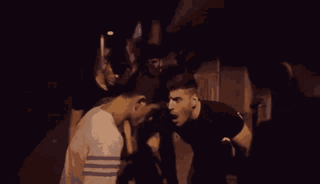 a group of men are standing next to each other in a dark room at night .