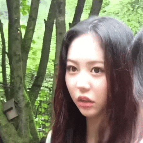 a close up of a woman 's face in front of trees .