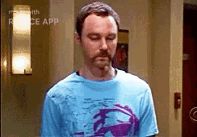 a man with a beard is wearing a blue shirt and a purple shirt .