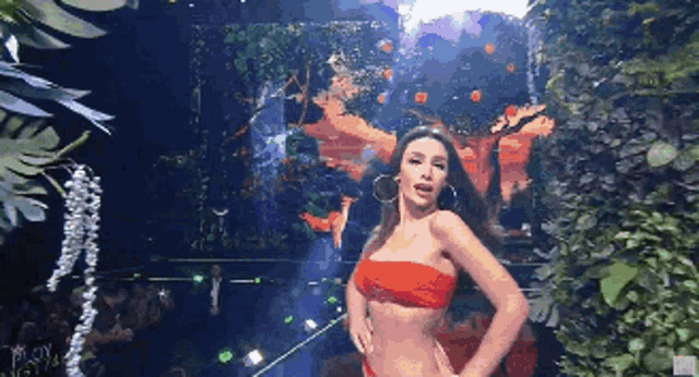 a woman in a red bikini is dancing on a stage in front of a crowd .