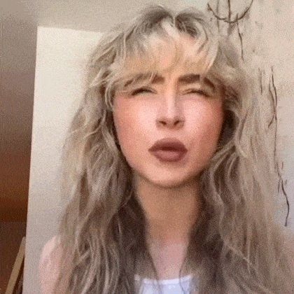 a woman with long blonde hair and bangs is making a face .