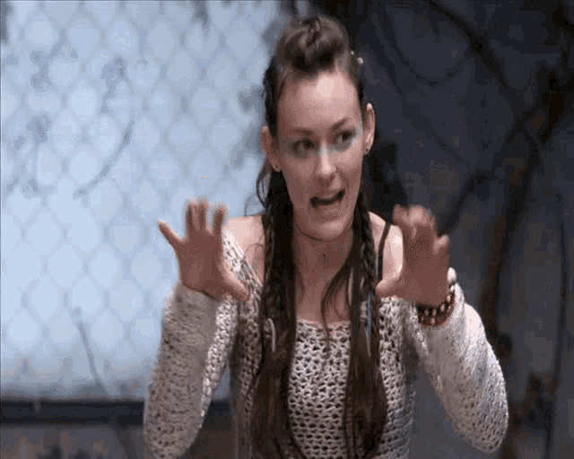 a woman in a white sweater is making a funny face with her hands outstretched