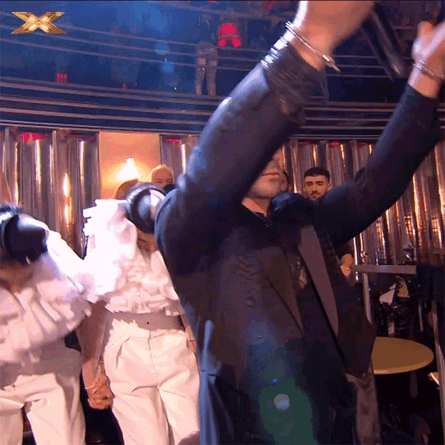 a man in a suit is holding a microphone in front of an x logo