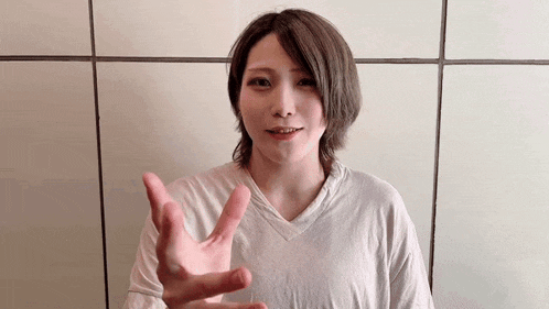 a young woman is giving a peace sign with her hand .