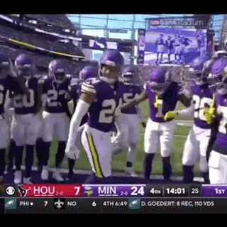 a group of football players are standing on a field in a stadium .