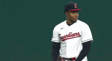 a baseball player wearing a guardians jersey stands on the field