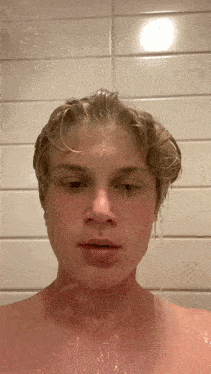 a young man is taking a shower with water coming out of his nose