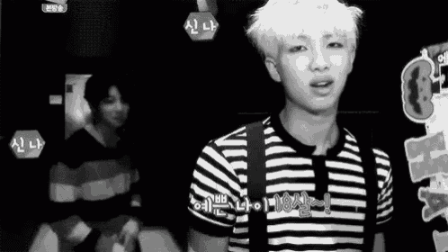 a black and white photo of a man wearing a striped shirt and a backpack .