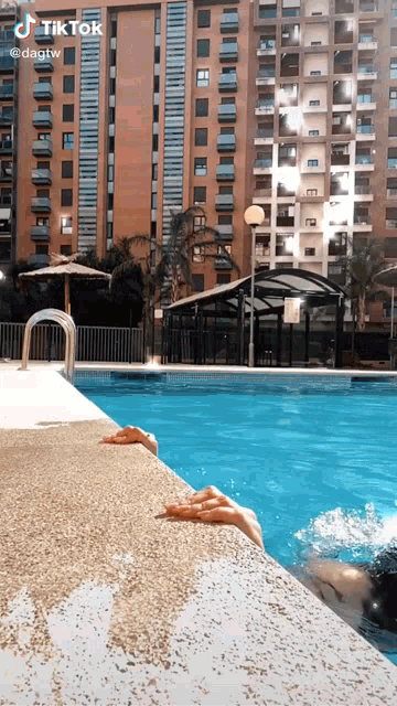 a person 's feet are sticking out of a swimming pool in front of a building that says tiktok