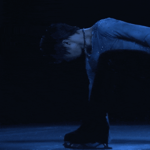 a man in a blue shirt and black pants is kneeling down on ice