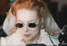 a woman wearing sunglasses and headphones is looking at a computer screen .