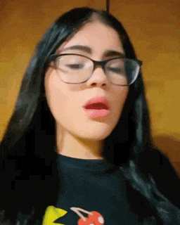 a woman wearing glasses and a black shirt with a cherry on it .