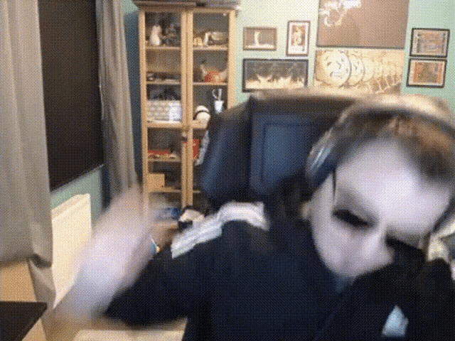 a person wearing headphones and a mask is sitting in front of a computer