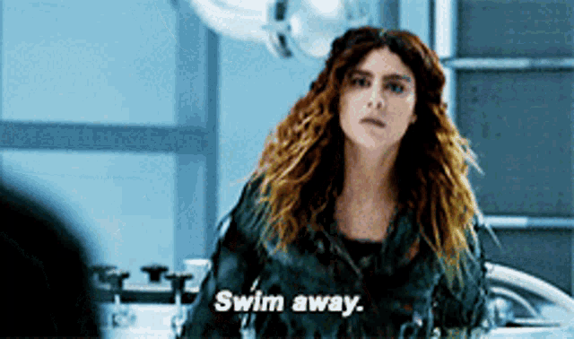 a woman says " swim away " while standing in a dark room