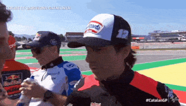 a man wearing a castrol hat is talking to another man
