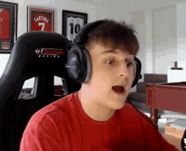 a man wearing headphones and a red shirt is sitting in front of a pool table