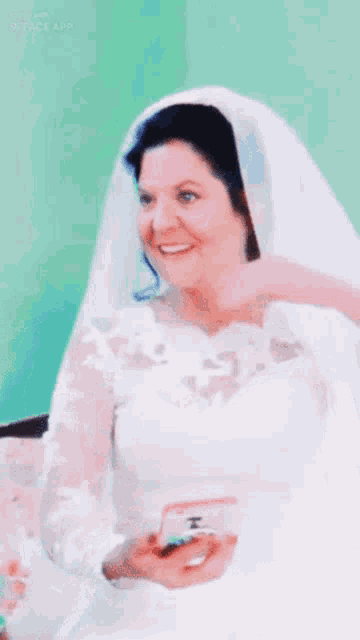 a woman in a wedding dress is smiling and holding a phone