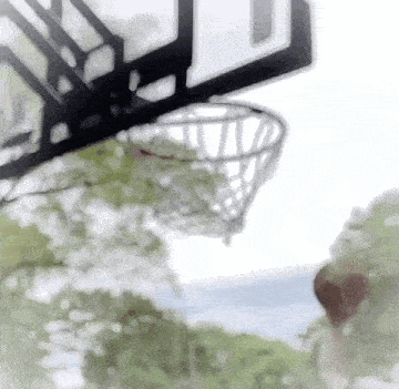 a basketball is going through a basketball hoop on a sunny day .