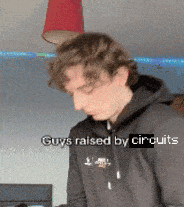 a man wearing a black hoodie with the words " guys raised by circuits " written on it