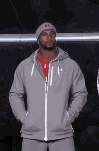 a man wearing a grey under armour jacket and a beanie