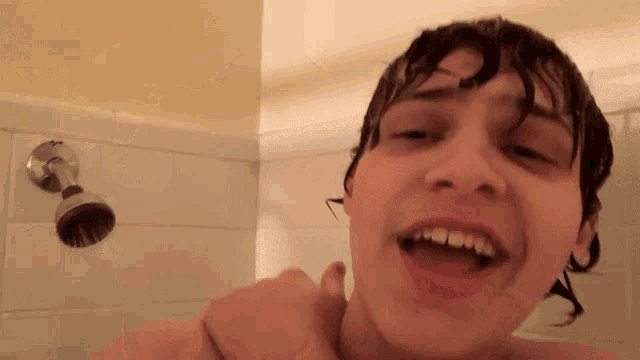 a young man is taking a shower with his mouth open
