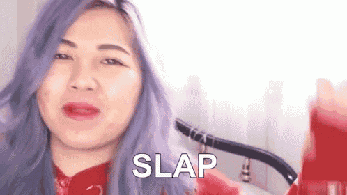 a woman with purple hair is wearing a red sweater and making a face .