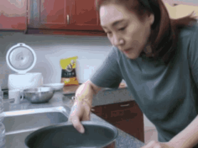 a woman is washing a pot in a kitchen sink