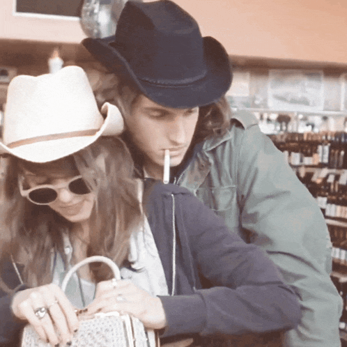 a man in a cowboy hat is smoking a cigarette next to a woman