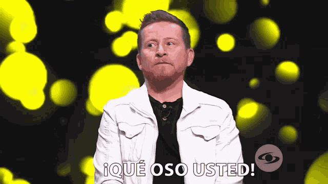 a man in a white jacket stands in front of a sign that says que oso usted