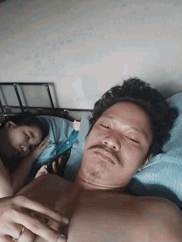 a man laying on a bed holding a baby with a ring on his finger