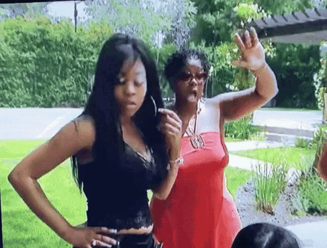 a woman in a red dress is standing next to another woman in a black shirt .