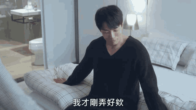 a man in a black shirt is laying on a bed with chinese writing