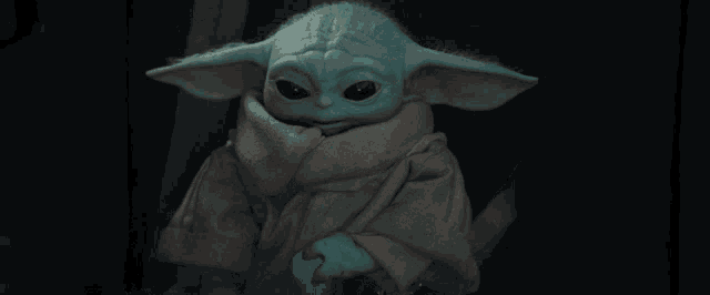 a baby yoda is holding a blue object in his hand