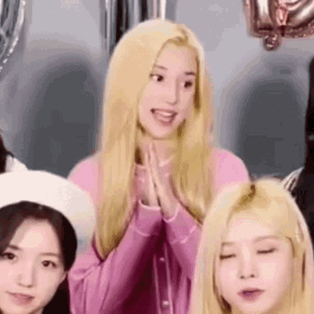a group of girls are sitting next to each other and one of them is wearing a pink shirt .