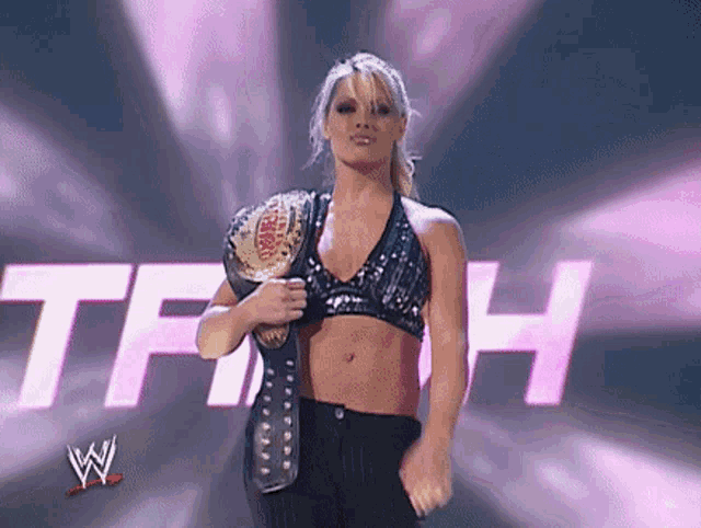 a female wrestler is holding a world heavyweight wrestling championship belt