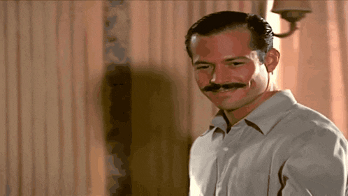 a man with a mustache wearing a white shirt is smiling