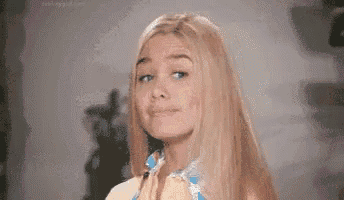 a woman with long blonde hair is smiling and making a funny face .